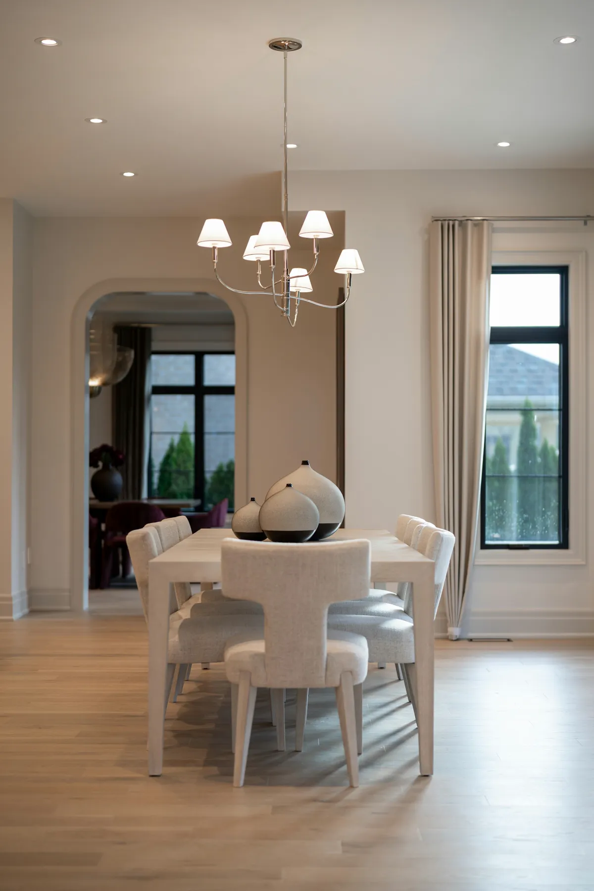 Dining room with a wood table and upholstered chairs on light oak plank flooring