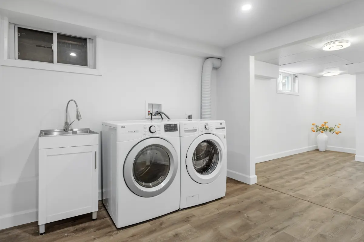 Laundry room with a washer, dryer and sink on light wood-look plank flooring